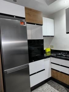 a kitchen with white cabinets and a stainless steel refrigerator at Bel appartement à ifrane in Ifrane