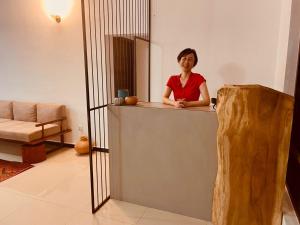 a woman sitting at a counter in a room with a mirror at Bees Airport Hotel in Katunayaka
