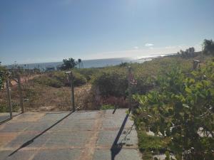 a gate to a garden with the ocean in the background at Chalé Braga in Cajueiro
