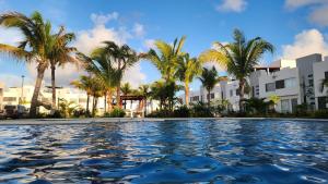 a pool with palm trees in front of a building at Casa 3 recamaras con alberca compartida Acapulco diamante in General Juan N Alvarez International Airport