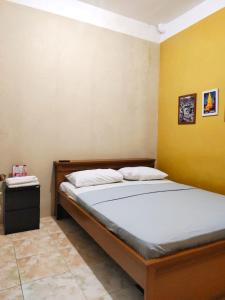 NgabeanOmah Cahyo Homestay的卧室里有一张床和一面黄色的墙