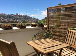 a wooden bench sitting on a balcony with potted plants at TANA-JACARANDA in Antananarivo