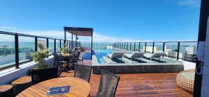 a balcony with tables and chairs and a swimming pool at #FLAT425 Get One - João Pessoa - Brasil in João Pessoa