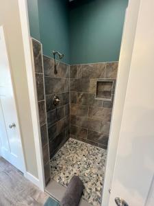 a walk in shower in a bathroom with green walls at Private Cabin on 90 Acres! in Wright City