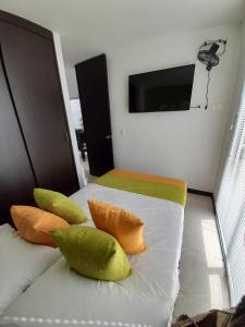 a bedroom with a bed with pillows and a tv on the wall at Apartamentos con piscina en zona turistica in Montenegro