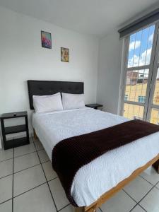 a bedroom with a large bed and a large window at Departamento Lotería in Morelia