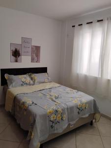 a bedroom with a bed with a blue comforter and yellow flowers at AP térreo-Rio das Ostras próx Enseada -Costazul in Rio das Ostras