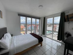 a bedroom with a bed and large windows at Departamento Lotería in Morelia