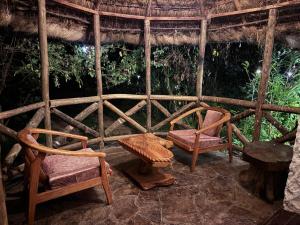 una stanza con due sedie e una panca e un tetto di paglia di Podocarpus Cottages -02 a Naro Moru Altre 41 foto