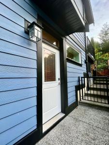 una puerta blanca en el costado de una casa azul en Hope's Happy Suite, en Nanaimo