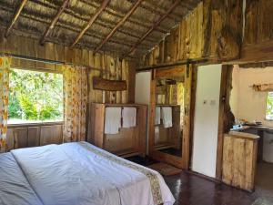 a bedroom with a bed in a room with wooden walls at Podocarpus Cottages -02 in Naro Moru