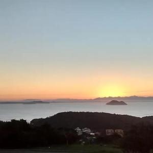 a sunset over the ocean with a house in the foreground at Buzios Suites - com Garagem in Búzios
