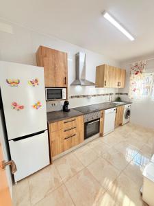 a kitchen with a white refrigerator and wooden cabinets at Villa del sol in Creixell