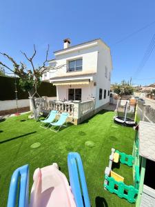 a yard with chairs and playground equipment in front of a house at Villa del sol in Creixell