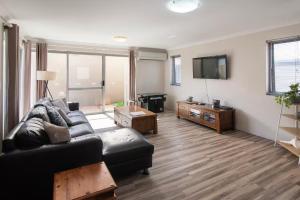 a living room with a black couch and a flat screen tv at Marina Family Beachscape in Geographe