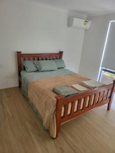 a bedroom with a large bed with a wooden frame at Spacious Karnup Home with 4 Bedrooms Modern Kitchen & Private Parking in Karnup