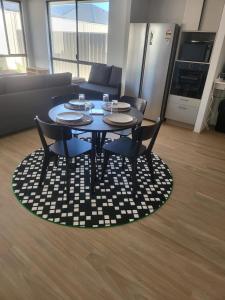 a table with four chairs and a couch in a living room at Spacious Karnup Home with 4 Bedrooms Modern Kitchen & Private Parking in Karnup
