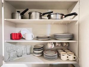 a cupboard filled with dishes and pots and pans at 3 Bedroom Apartment - 5 Beds in Abbotsford
