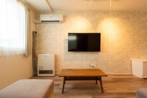 札幌市にあるYuuzen N11 Condominium 新築 市場まで徒歩すぐ 駐車場完備のレンガの壁にテレビ付きのリビングルーム