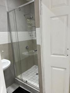 a shower with a glass door next to a sink at Marble inn accommodation in Durban