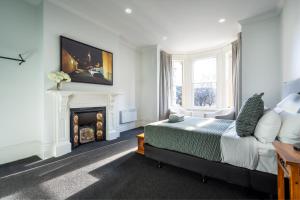 a white bedroom with a bed and a fireplace at The Stuart Street Terraced House in Dunedin