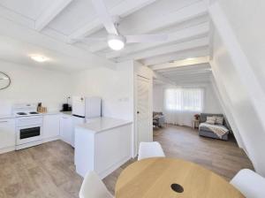 a kitchen with white cabinets and a wooden table at Central Bargara Beach Bungalow by UG in Bargara +30 photos
