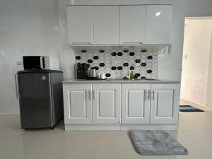 Una cocina con gabinetes blancos y un refrigerador. en Lycanhikers Apartments, en Panglao