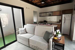 a living room with a white couch and a kitchen at Amora Maria Residencial in Cascavel