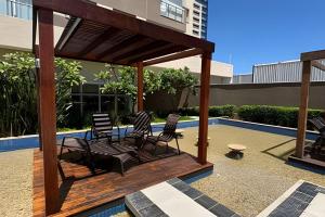 a wooden pergola with chairs and a pool at Apt Luxo VI no Shopping Df Plaza in Brasilia