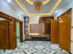 a living room with a large tv and a large room at Karachi Family Guest House in Karachi
