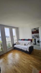 Un dormitorio con una cama en una habitación con ventanas. en Paris 16eme vista a la torre eiffel, en Boulogne-Billancourt