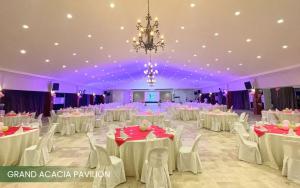 a banquet hall with white tables and chairs and a chandelier at Acacia Hotel Bacolod in Bacolod