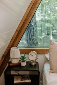 a clock on a table next to a window at Wilewood A-Frame, Romantic Treehouse Getaway, Hot Tub in Abbeville