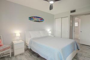 a white bedroom with a bed and a chair at Ocean Side Complex with Heated Pool B-15 in Saint Augustine +25 photos