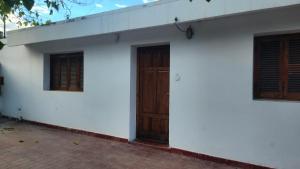 a white building with a wooden door and two windows at Casa Famatina in Chilecito