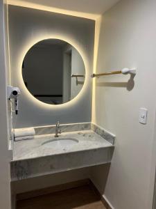 a bathroom with a sink with a round mirror at Hot Springs Flat Apart-Hotel Master Luxo com Banheira in Caldas Novas +280 photos