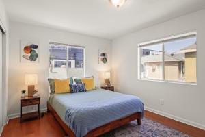 a bedroom with a bed and two windows at Dazzling 4BR Near Amazon Studios Venice Beach in Los Angeles