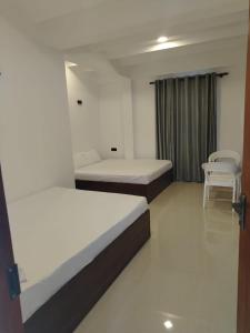 a room with two beds and two chairs in it at Kandy Nivahana Heights Homestay in Kandy