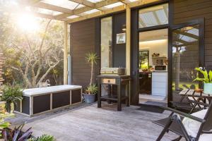 a screened in porch with a tub and a kitchen at Creekside at Kūaotunu in Matarangi