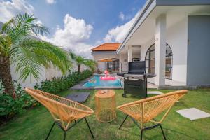 Un patio trasero con piscina y dos sillas y una parrilla. en Villa Intisar - luxury oasis in Canggu, en Canggu