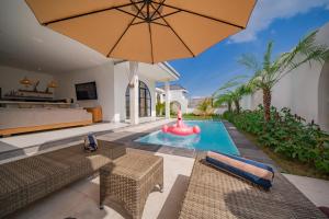 Una piscina al aire libre con sombrilla y sillas y una piscina en Villa Intisar - luxury oasis in Canggu, en Canggu