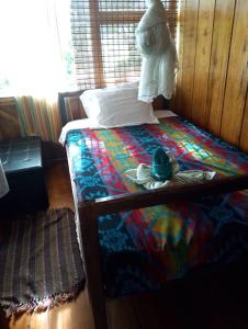 a bed with a colorful blanket and a hat on it at Cabaña Familiar Mindo in Mindo +5 photos