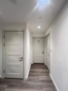 an empty hallway with white walls and white doors at Cozy Luxxe Apartment Brentford in Brentford