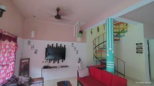 a living room with a red couch and a tv at yercaud Happy valley cottage in Yercaud +11 photos