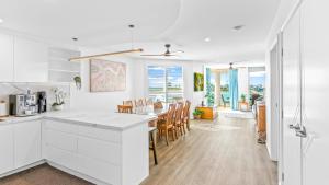 a kitchen and dining room with white cabinets at Mirage 801 in Tuncurry