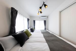 a large white bed in a room with a window at Amp Flat TFK西新駅前 in Fukuoka