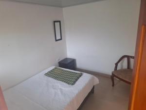 a small bedroom with a bed and a chair at Penthouse - Altos de Iguaque in Gámbita +3 photos