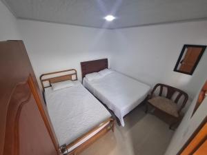 two beds in a small room with a chair at Penthouse - Altos de Iguaque in Gámbita