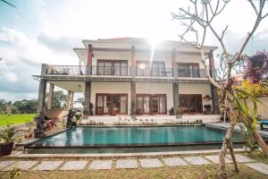 a house with a swimming pool in front of it at Villa Popolan and Guest House in Ubud