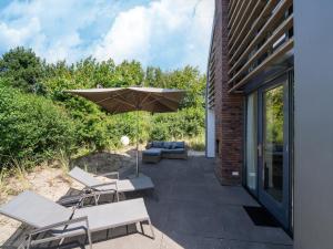 a patio with chairs and an umbrella next to a building at Holiday home Waterland for six Person in Egmond aan den Hoef
